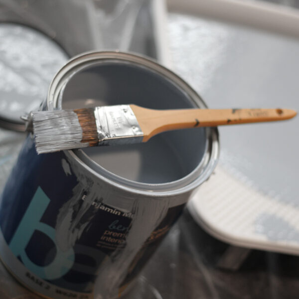 Can of gray paint with paint brush