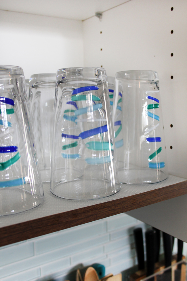 Shelf liner under teal and blue striped drinking glasses