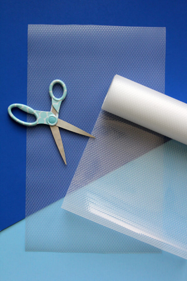 clear shelf liner and scissors on blue background