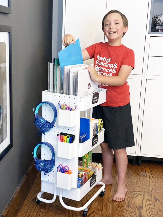 Boy getting school supplies from rolling homeschool cart in kitchen