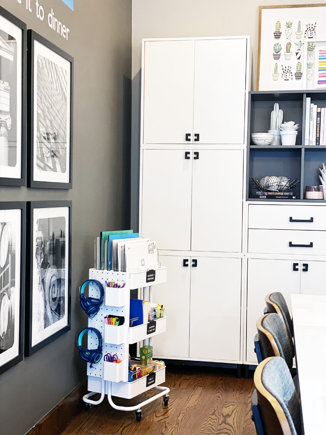 Rolling school cart in corner of kitchen with white cabinets