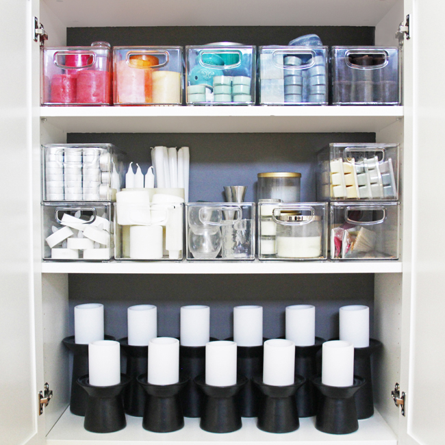 an organized candle storage cabinet with candles in rainbow order