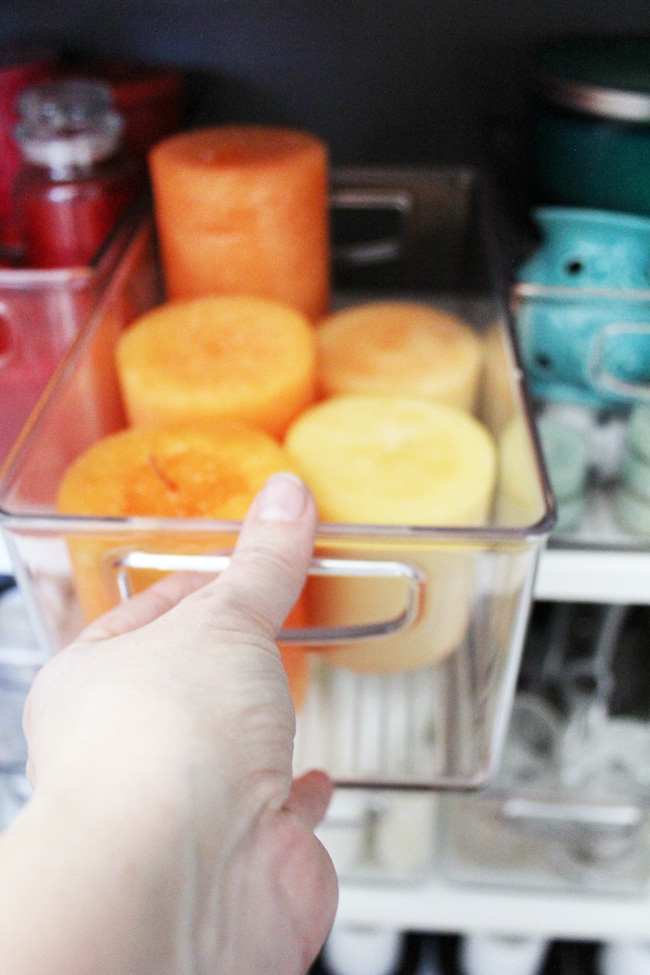 Candles organized in clear bins with handles